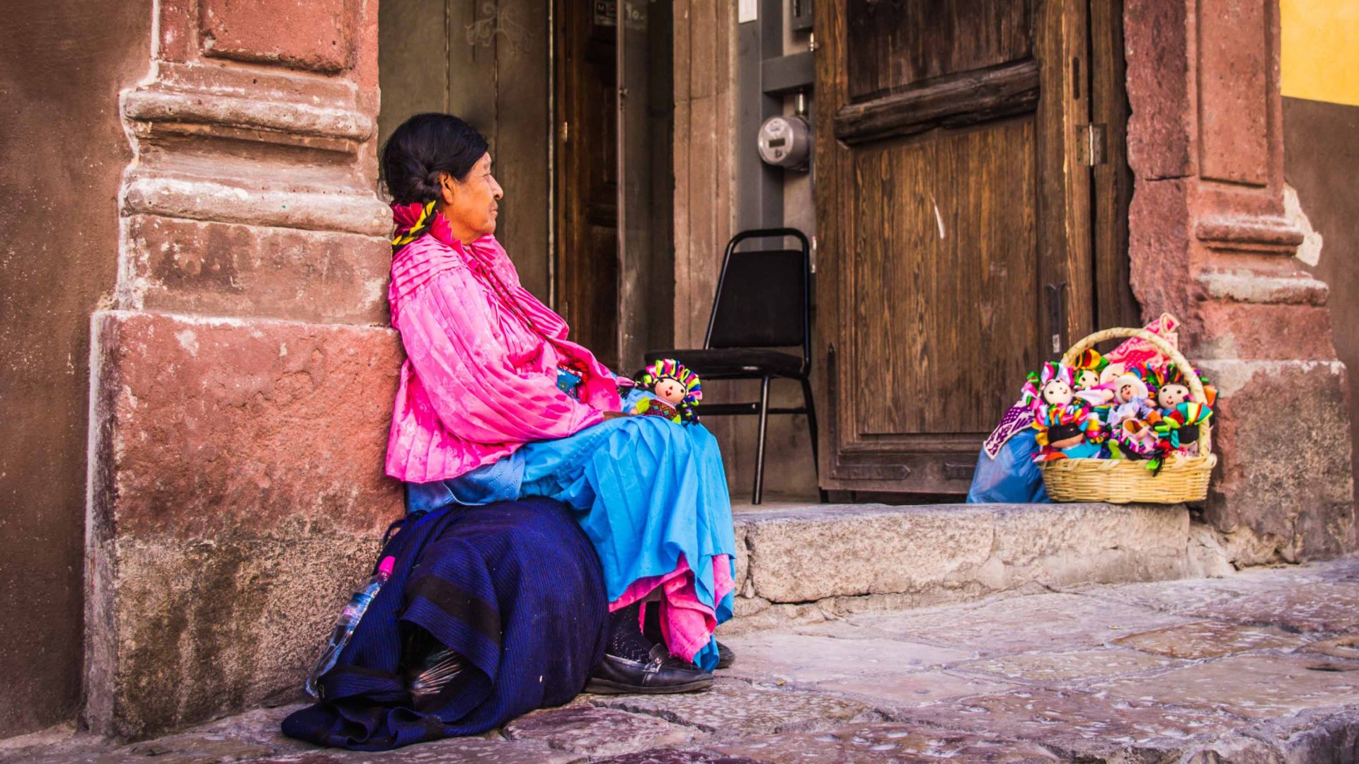 An Indigenous woman in Mexico sells dolls on the street.