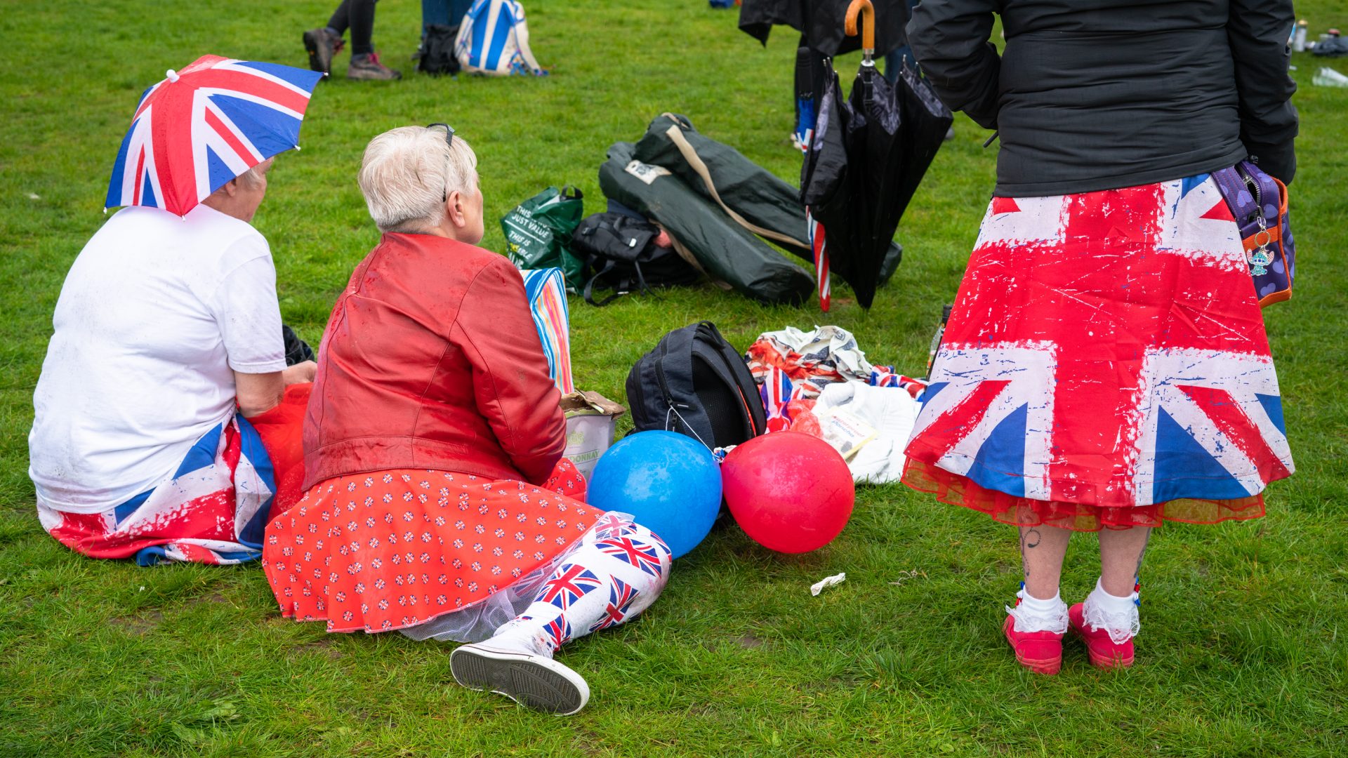 Picnickers wearing Union Jack clothing in the park.