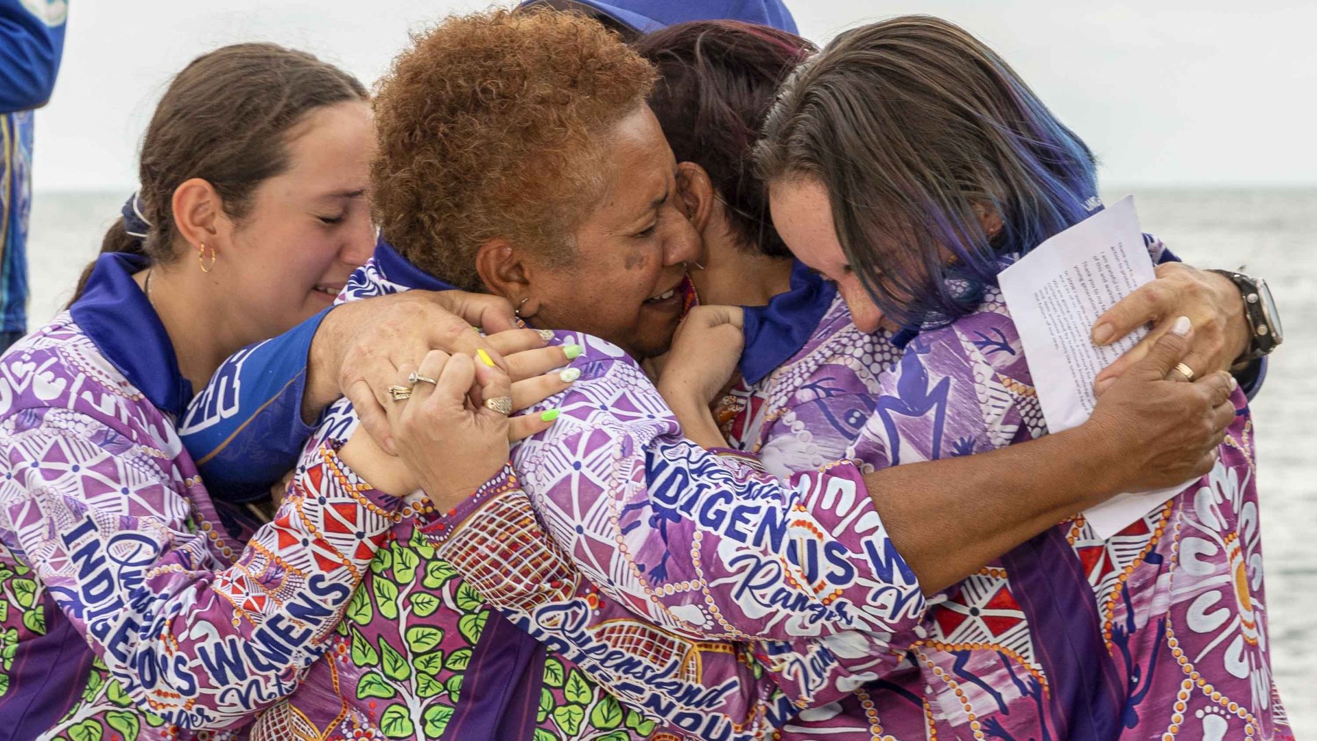 A group of Indigenous rangers hug each other in celebration of a prize win..