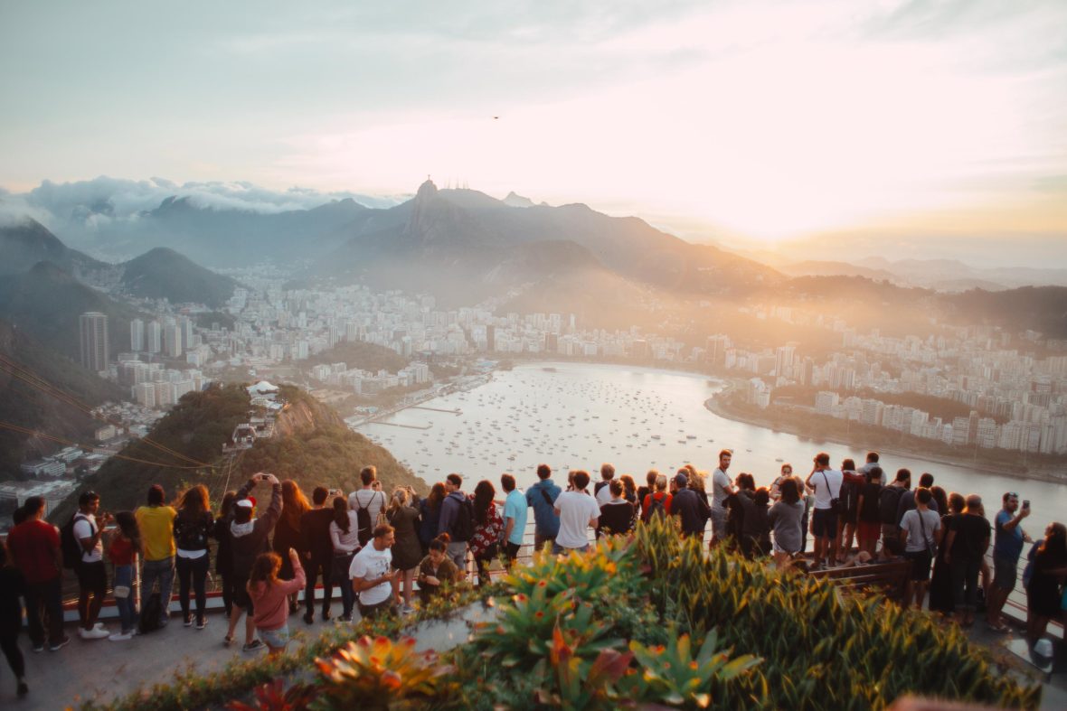 A big group of tourists look out over the mountains and water in Rio de Janeiro.