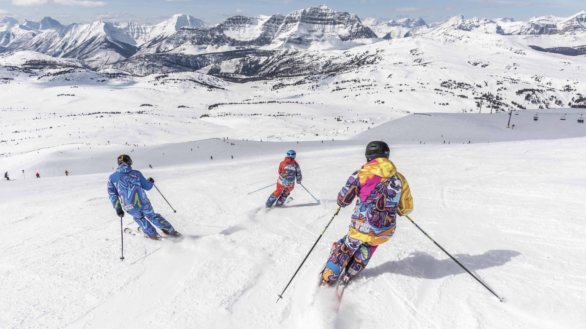 Three skiers ski down a snow covered mountain.