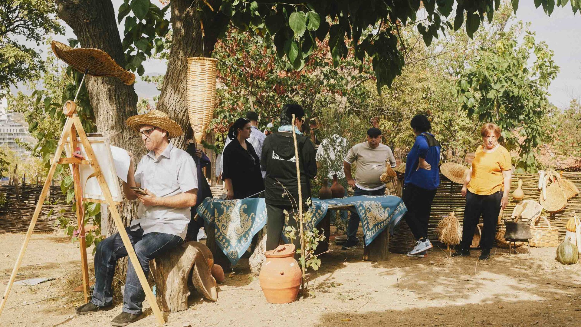 A musician plays while people sit under a tree.
